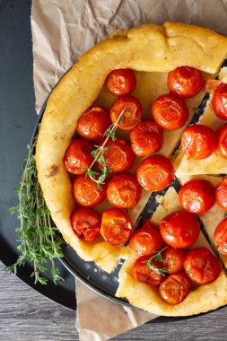 Puf böreği çiğ domatesli ve koyu ahşap zemin üzerine kekik kiraz domates ile ev yapımı tart. Domates tart tatin. Rustik tarzı.