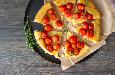 Puf böreği çiğ domatesli ve koyu ahşap zemin üzerine kekik kiraz domates ile ev yapımı tart. Domates tart tatin. Rustik tarzı.