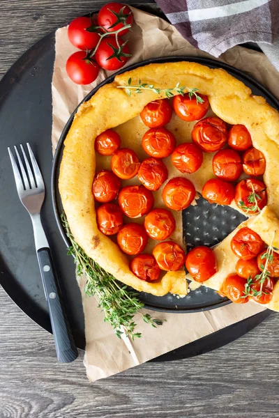 Puf böreği çiğ domatesli ve koyu ahşap zemin üzerine kekik kiraz domates ile ev yapımı tart. Domates tart tatin. Rustik tarzı.