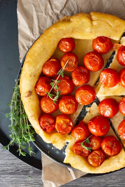 Puf böreği çiğ domatesli ve koyu ahşap zemin üzerine kekik kiraz domates ile ev yapımı tart. Domates tart tatin. Rustik tarzı.