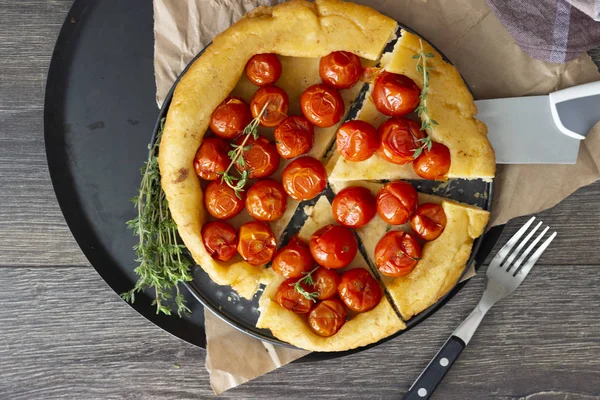 Puf böreği çiğ domatesli ve koyu ahşap zemin üzerine kekik kiraz domates ile ev yapımı tart. Domates tart tatin. Rustik tarzı.