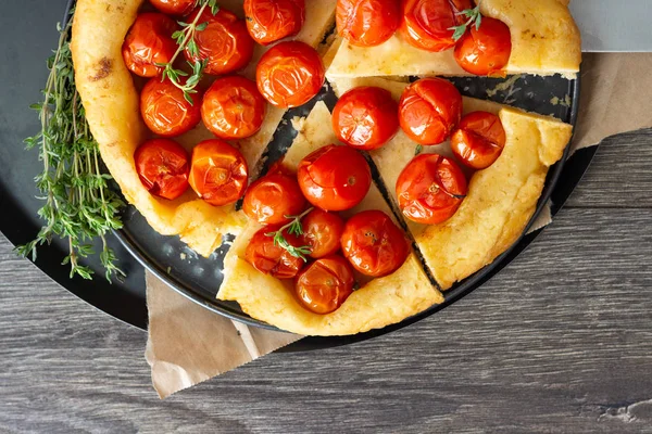 Puf böreği çiğ domatesli ve koyu ahşap zemin üzerine kekik kiraz domates ile ev yapımı tart. Domates tart tatin. Rustik tarzı.