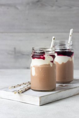 Doğal yoğurt ve siyah frenk üzümü çikolata ve muz yüzlü iki şişe. Lezzetli ve sağlıklı bir kahvaltı kavramı. Seçici odak. Kopya alanı.