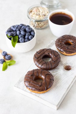 Kahvaltı kavramı: çörek çikolata sır, bir fincan kahve, granola ve açık gri renkli nane ile taze yaban mersini ile. Seçici odak, kopya alanı 