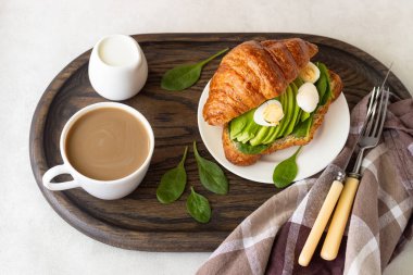 Kruvasan yeşil salata, avokado ve yumurta bir koyu ahşap tepsi. Kahvaltı, brunch veya öğle yemeği kavramı.