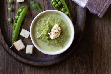 Yeşil bezelye çorbası kase ıspanak ve ahşap rustik kesme tahtası üzerinde krema ile.