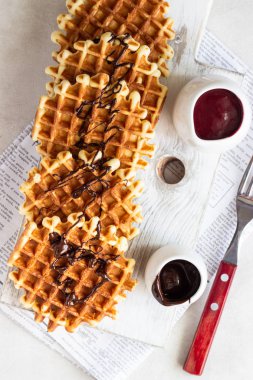 Liege stil Belçika Waffle bir beyaz tahta kesme tahtası üzerine çikolata sosu ile tepesinde