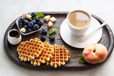 Taze yaban mersini, şeftali, çikolata sosu ve bir fincan kahve bir rustik ahşap kesme tahtası üzerinde Belçika Waffle. Liege stil Belçika Waffle. Kahvaltı ve öğle yemeği kavramı.