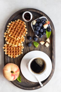 Taze yaban mersini, şeftali, çikolata sosu ve bir fincan kahve bir rustik ahşap kesme tahtası üzerinde Belçika Waffle. Liege stil Belçika Waffle. Kahvaltı ve öğle yemeği kavramı.