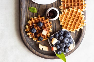 Taze yaban mersini, şeftali ve rustik ahşap kesme tahtası üzerine çikolata sosu ile Belçika Waffle. Liege stil Belçika Waffle. Kahvaltı ve öğle yemeği kavramı.