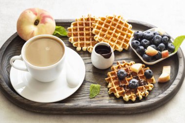 Taze yaban mersini, şeftali, çikolata sosu ve bir fincan kahve bir rustik ahşap kesme tahtası üzerinde Belçika Waffle. Liege stil Belçika Waffle. Kahvaltı ve öğle yemeği kavramı.