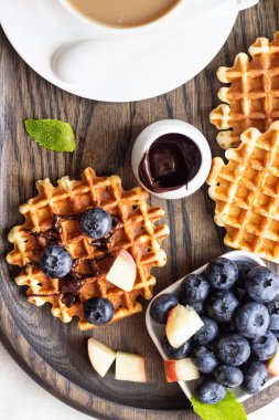 Taze yaban mersini, şeftali ve rustik ahşap kesme tahtası üzerine çikolata sosu ile Belçika Waffle. Liege stil Belçika Waffle. Kahvaltı ve öğle yemeği kavramı.