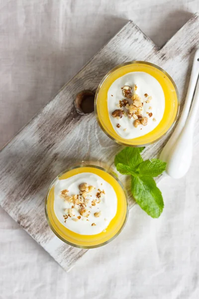 Peach dessert (mousse) with natural yoghurt, walnuts and mint in portion glasses