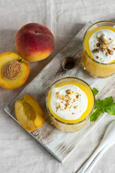 Peach dessert (mousse) with natural yoghurt, walnuts and mint in portion glasses