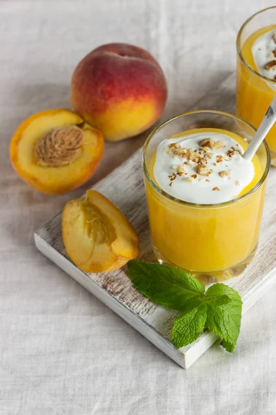 Peach dessert (mousse) with natural yoghurt, walnuts and mint in portion glasses