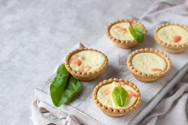 Mini tartlets krem peynir dolum ve beyaz tahta kesme tahtası somon ile.