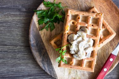 Rustik bir arka plan üzerinde ahşap bir tabakta Mısır ve mantar kremalı sos ile tuzlu waffle
