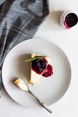 New York tarzı cheesecake siyah frenk üzümü sos ve biberiye ışık arka plan üzerinde gri plaka üzerinde parça.