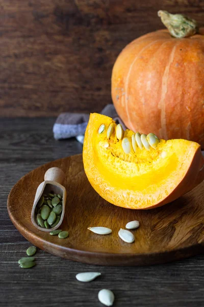 Taze turuncu kabak çiğ kabak çekirdeği, rustik tarzı ile ahşap bir tabakta. Turuncu Halloween balkabağı. Tatil dekorasyon.