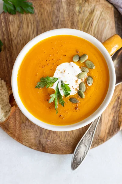 Krema, maydanoz ve ışık arka plan üzerinde kabak çekirdeği ile kavrulmuş balkabağı çorbası. 