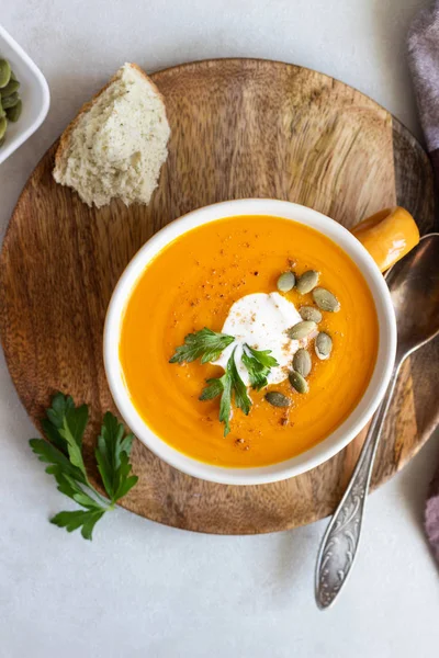 Krema, maydanoz ve ışık arka plan üzerinde kabak çekirdeği ile kavrulmuş balkabağı çorbası. 