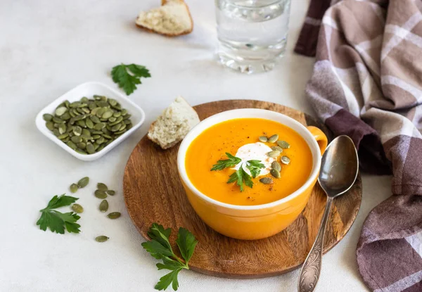 Krema, maydanoz ve ışık arka plan üzerinde kabak çekirdeği ile kavrulmuş balkabağı çorbası. 