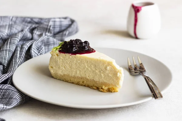 New York tarzı cheesecake siyah frenk üzümü sos ve biberiye ışık arka plan üzerinde gri plaka üzerinde parça.