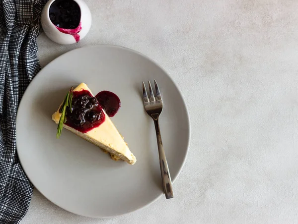 New York tarzı cheesecake siyah frenk üzümü sos ve biberiye ışık arka plan üzerinde gri plaka üzerinde parça.