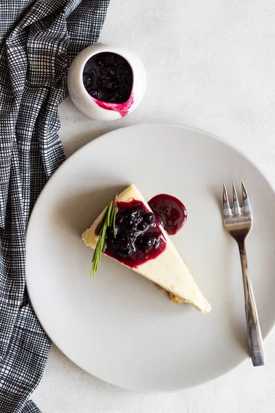 New York tarzı cheesecake siyah frenk üzümü sos ve biberiye ışık arka plan üzerinde gri plaka üzerinde parça.