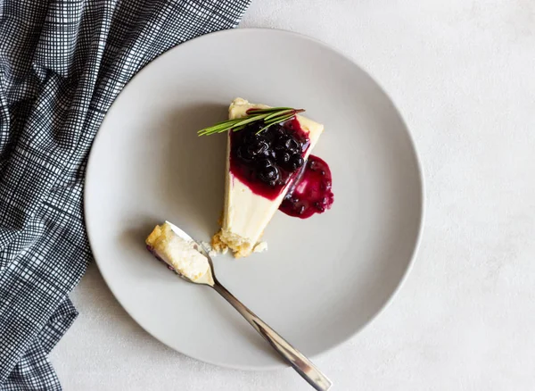 New York tarzı cheesecake siyah frenk üzümü sos ve biberiye ışık arka plan üzerinde gri plaka üzerinde parça.