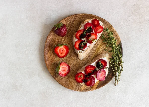 Bruschetta veya çilek, krem peynir veya ricotta, balsamik sirke ve kekik hafif bir arka plan üzerinde sandviç. Yaz Aperatif yiyecek. İtalyan kahvaltısı. İtalyan mutfağı.