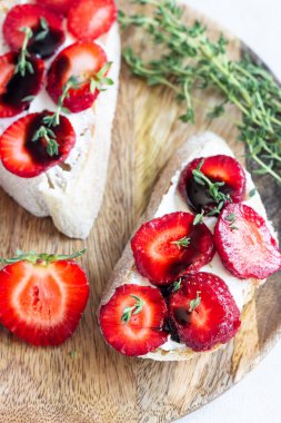 Bruschetta veya çilek, krem peynir veya ricotta, balsamik sirke ve kekik hafif bir arka plan üzerinde sandviç. Yaz Aperatif yiyecek. İtalyan kahvaltısı. İtalyan mutfağı.