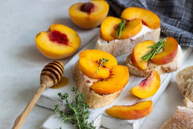 Baget şeftali, peynir, bal ve biberiye ile bir beyaz tahta kesme kurulunda görev yapmaktadır. Bruschetta veya sandviç piknik için. Meyve yaz Aperatif. Geleneksel İtalyan yemekleri.