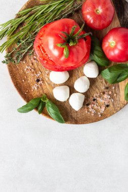 Mozzarella ve domates fesleğen yaprakları, biberiye ve kekik bir ahşap plaka üzerinde. İtalyan salata caprese için malzemeler. Kopya alanı