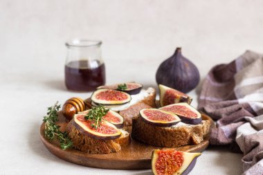 Ricotta (krem peynir), incir, bal ve kekik ile mini bruschetta (tost ya da sandviç) ahşap rustik tabakta. Sağlıklı gıda kavramı. 
