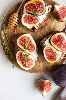 Ricotta (krem peynir), incir, bal ve kekik ile mini bruschetta (tost ya da sandviç) ahşap rustik tabakta. Sağlıklı gıda kavramı. 