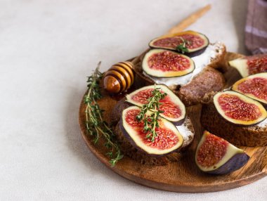 Ricotta (krem peynir), incir, bal ve kekik ile mini bruschetta (tost ya da sandviç) ahşap rustik tabakta. Sağlıklı gıda kavramı. 