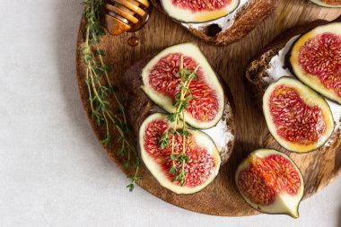 Ricotta (krem peynir), incir, bal ve kekik ile mini bruschetta (tost ya da sandviç) ahşap rustik tabakta. Sağlıklı gıda kavramı. 