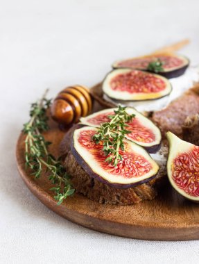 Ricotta (krem peynir), incir, bal ve kekik ile mini bruschetta (tost ya da sandviç) ahşap rustik tabakta. Sağlıklı gıda kavramı. 