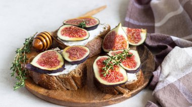 Ricotta (krem peynir), incir, bal ve kekik ile mini bruschetta (tost ya da sandviç) ahşap rustik tabakta. Sağlıklı gıda kavramı. 