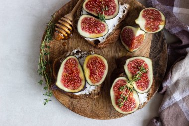 Ricotta (krem peynir), incir, bal ve kekik ile mini bruschetta (tost ya da sandviç) ahşap rustik tabakta. Sağlıklı gıda kavramı. 