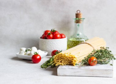 Makarna yemek pişirmek için malzemeler. Spagetti, cherry domates, kekik, biberiye, zeytinyağı ve açık gri renkli üzerinde mozzarella. İtalyan pasta malzemeler.