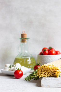 Makarna yemek pişirmek için malzemeler. Spagetti, cherry domates, kekik, biberiye, zeytinyağı ve açık gri renkli üzerinde mozzarella. İtalyan pasta malzemeler.