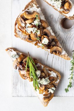 Bütün tahıl çavdar ekmeği tost krem peynir veya ricotta, mantar ve beyaz tahta kesme tahtası üzerinde otlar ile.