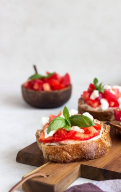 Doğranmış domates, mozzarella peyniri ve fesleğen ahşap kesme tahtası üzerinde İtalyan bruschetta. 