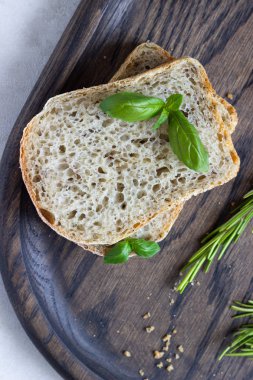 Biberiye, fesleğen ve koyu ahşap tepsi üzerine zeytin yağı ile taze pişmiş Çavdar ekmek. 