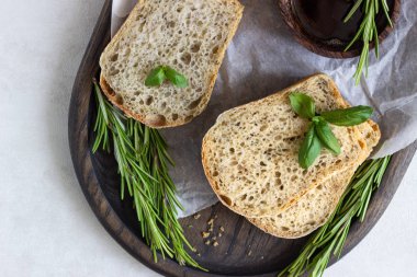 Biberiye, fesleğen ve koyu ahşap tepsi üzerine zeytin yağı ile taze pişmiş Çavdar ekmek. 
