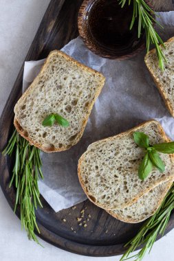 Biberiye, fesleğen ve koyu ahşap tepsi üzerine zeytin yağı ile taze pişmiş Çavdar ekmek. 