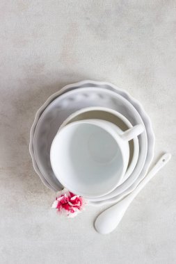 Farklı beyaz seramik tabak açık gri arka planı ayarla. Zarif beyaz sofra. Minimalist natürmort. Yumuşak ışık, yüksek anahtar. 