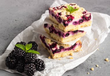 Böğürtlen ile peynirli kek barlar ve streusel ile nane yaprakları pişirme kağıdı beyaz.